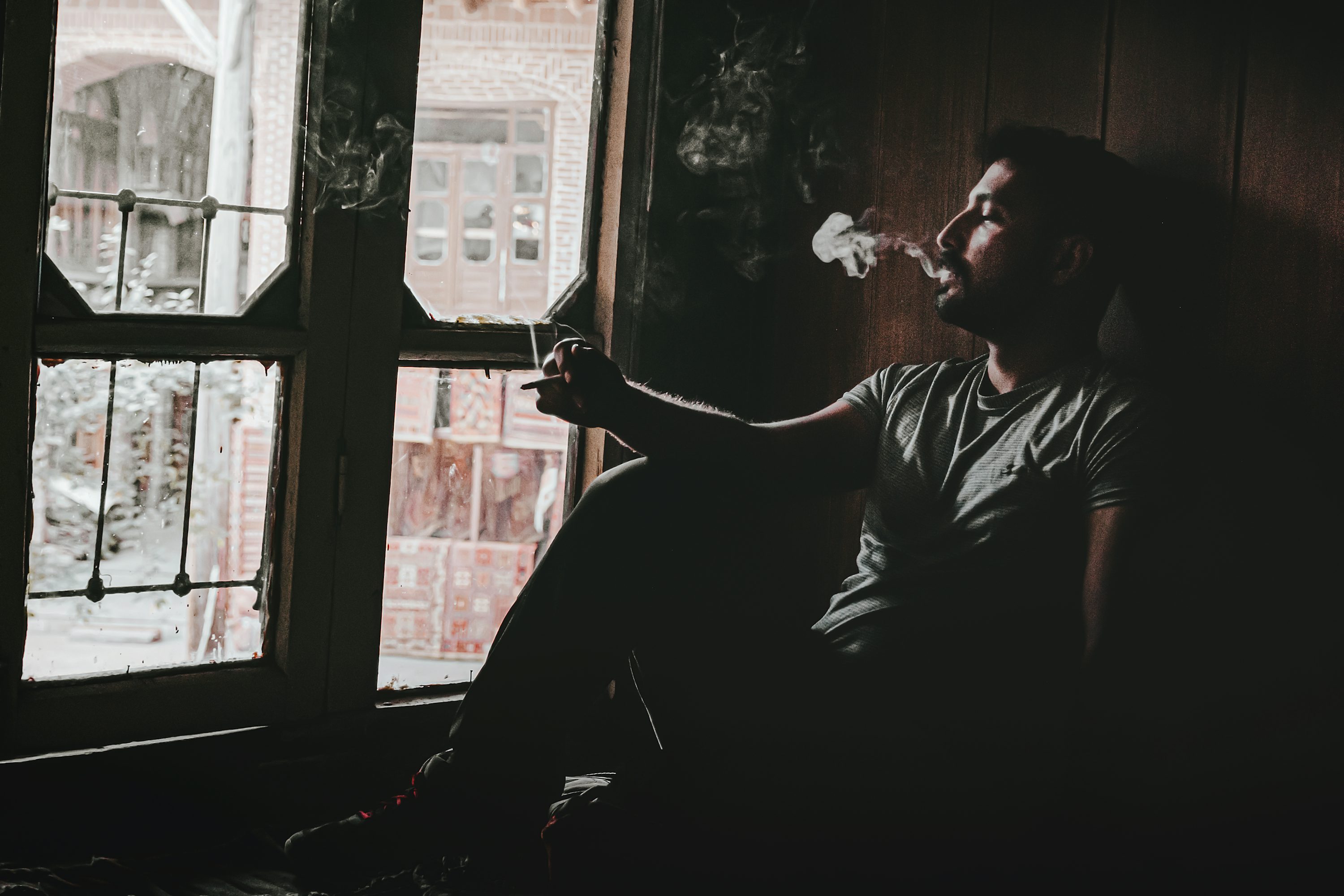 a man smoking by the door of the house